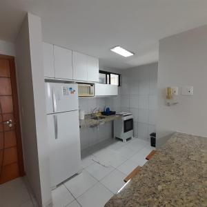a kitchen with white cabinets and a white refrigerator at Apartamento em João Pessoa in João Pessoa