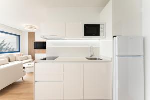 eine Küche mit weißen Schränken und einem weißen Kühlschrank in der Unterkunft Alsol Los Caribes 1 in Playa del Ingles