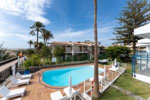 ein Swimmingpool mit Stühlen und ein Haus in der Unterkunft Alsol Los Caribes 1 in Playa del Ingles