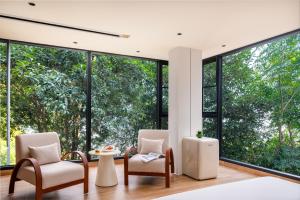 Un dormitorio con dos sillas y grandes ventanales. en Guilin Lakeview Boutique Lodge, en Guilin