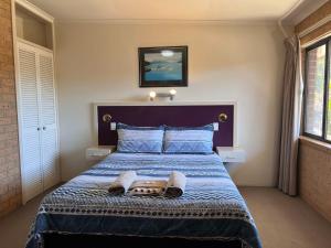 ein Schlafzimmer mit einem Bett mit einer blauen Bettdecke in der Unterkunft Cann Valley Motel in Cann River + 18 Fotos