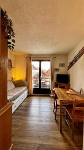 a living room with a bed and a table and a room with a window at L'ETERLOU, Studio Centre station in Risoul