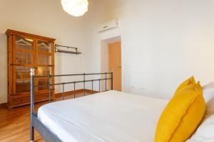 a bedroom with a bed with white sheets and yellow pillows at Apartamentos Sherry Center in Jerez de la Frontera