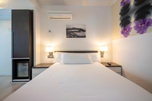 1 cama blanca grande en una habitación con 2 lámparas en Hotel Punta Monpas, en San Sebastián