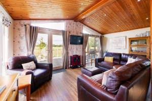 sala de estar con sofás de cuero y TV en Immaculate 3-Bedroom Private Lodge near York, en York