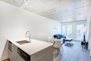 Il comprend une cuisine blanche avec un évier et un salon. dans l'établissement Corporate Stays Le Shaughn 1 Bedroom, à Montréal
