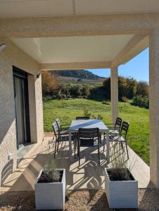 een patio met een tafel en stoelen op een veranda bij L'échappée Bourguignonne in La Roche-Vineuse