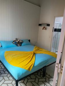 a bed with a yellow blanket on top of it at Blue Sapphire guest house in Caucaia
