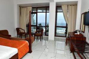 een slaapkamer met een bed en een eetkamer met uitzicht bij By The Bay Kovalam in Trivandrum