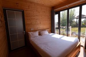 a bed in a wooden room with a large window at Homestay Đồi Mây Lộc Tân Bảo Lộc in Bảo Lâm