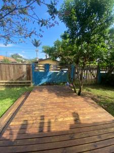 een houten terras met een boom in een tuin bij Cabana da palmeira in Piçarras