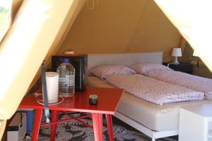 una cama en una tienda de campaña con una mesa roja en Alpakkaparken Glamping med parktilgang, 