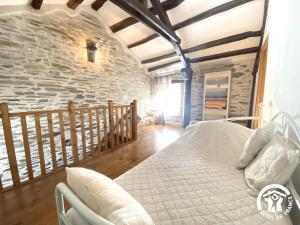 a bedroom with a bed and a stone wall at Dame nature in La Tourette-Cabardès