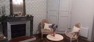a living room with two chairs and a fireplace at Le domaine du Champ Han in Saint-Hilaire-du-Harcouët