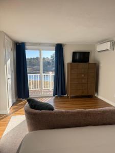 een woonkamer met een bank en een groot raam bij Waterfront Escape Hottub, Pets Ok, Pool Table in Dennis