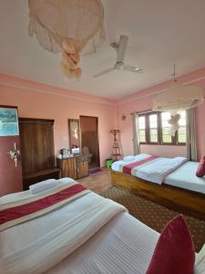 duas camas em um quarto com paredes rosa em Hotel Tree Tops em Sauraha