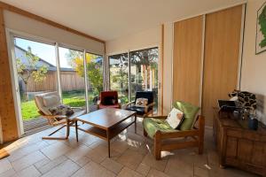 ein Wohnzimmer mit Tisch und Stühlen und Fenstern in der Unterkunft Confortable maison familiale à 5 minutes du lac in Saint-Simon