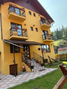 a yellow building with balconies and stairs in front of it at Cabana Dan Arieseni in Arieşeni