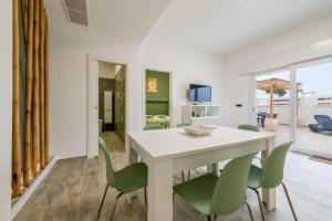 a dining room with a white table and green chairs at Fichi d'India Appartamenti in San Pietro in Bevagna