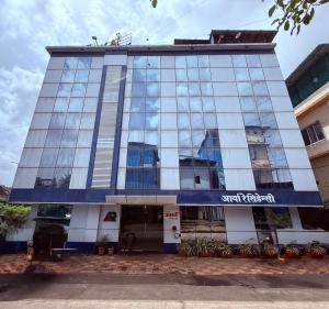 a tall glass building with a sign on it at Hotel Arya Residency Rabale in Airoli
