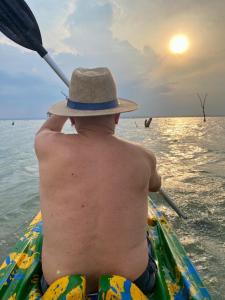 a man in a hat sitting in a boat in the water at Chácara Maranata in Manaus