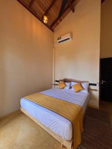 a bedroom with a bed with white sheets and yellow pillows at Tahini and Friends Surf, Yoga & Wellness in Ahangama