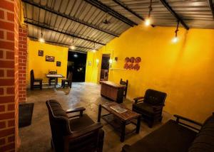 a room with a yellow wall with chairs and a table at The Tiger's Hill Retreat in Lagma +1 photo
