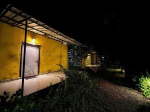 a yellow house at night with a lit up window at The Tiger's Hill Retreat in Lagma