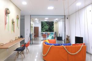 ein Wohnzimmer mit einer orangefarbenen Couch und Stühlen in der Unterkunft TACACÁ HOSTEL - Localização Privilegiada in Belém