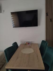 a wooden table with green chairs and a flat screen tv at Apartmant Novaković in Vrnjačka Banja