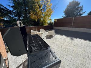 a barbecue grill on a patio with two chairs at Casa Abetos in Collado Mediano +67 photos