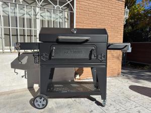 a black grill sitting on a sidewalk next to a building at Casa Abetos in Collado Mediano