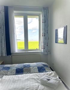 a bedroom with a bed and a window at Se 06 Haus Seeterrassen in Cuxhaven
