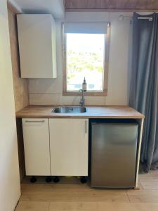 une petite cuisine avec un évier et une fenêtre dans l'établissement Kiwi Beach Bach - Hot Tub - 2 bed, à Whangapoua