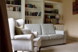 uma sala de estar com um sofá branco e uma cadeira em Ballyvara House em Doolin