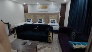 a hotel room with two beds and a couch at لانا العلا شقق مفروشة Lana Alula in Al-ʿUla