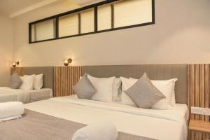 deux lits dans une chambre d'hôtel avec des oreillers blancs dans l'établissement The Travancore Palace Beach Resort, à Kovalam