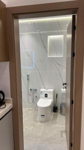 a white bathroom with a toilet and a shower at اجنحة دانة DANAT Suites الرياض حي اليرموك in Riyadh