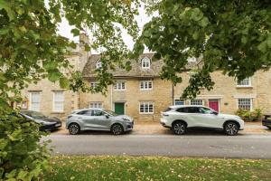 drei Autos auf einem Parkplatz vor einem Gebäude geparkt in der Unterkunft Cotswold Cottage- Central Witney in Witney