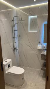 a white bathroom with a toilet and a shower at اجنحة دانة DANAT Suites الرياض حي اليرموك in Riyadh +9 photos