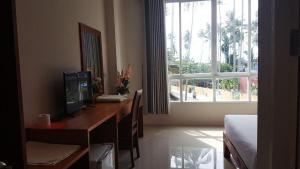 een kamer met een bureau, een televisie en een raam bij Noah's Ark Pool Residence and Villas in Nathon Bay