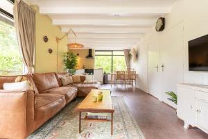 Una sala de estar con un sofá marrón y una mesa. en Bungalow Veldzicht | 4 personen - Vakantiepark De Kremmer, en Gasselte