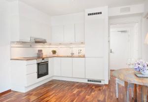 a kitchen with white cabinets and a wooden table at Seafront Luxury In Oslo in Oslo