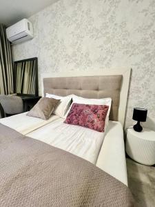 a bedroom with a white bed with a pink pillow at IN&P Apartment - top location in Veliko Tŭrnovo