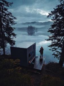 a person standing on a dock next to a trailer in the water at Birdbox Tokke 