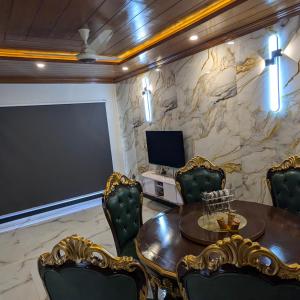 a room with a table and chairs and a television at AlFalah Guest House in Murree