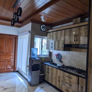 a kitchen with wooden cabinets and a stove top oven at AlFalah Guest House in Murree