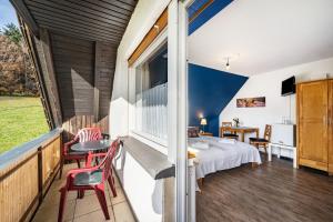 a room with a bed and chairs on a balcony at Café Pension Pfaus Heidburg in Mühlenbach