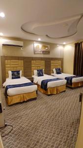a hotel room with three beds in a room at لانا العلا شقق مفروشة Lana Alula in Al-ʿUla
