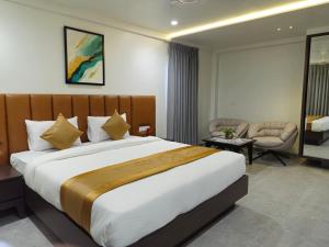 a hotel room with a large bed and a chair at Hotel The Golden Oaks, Kolhapur in Kolhapur +107 photos